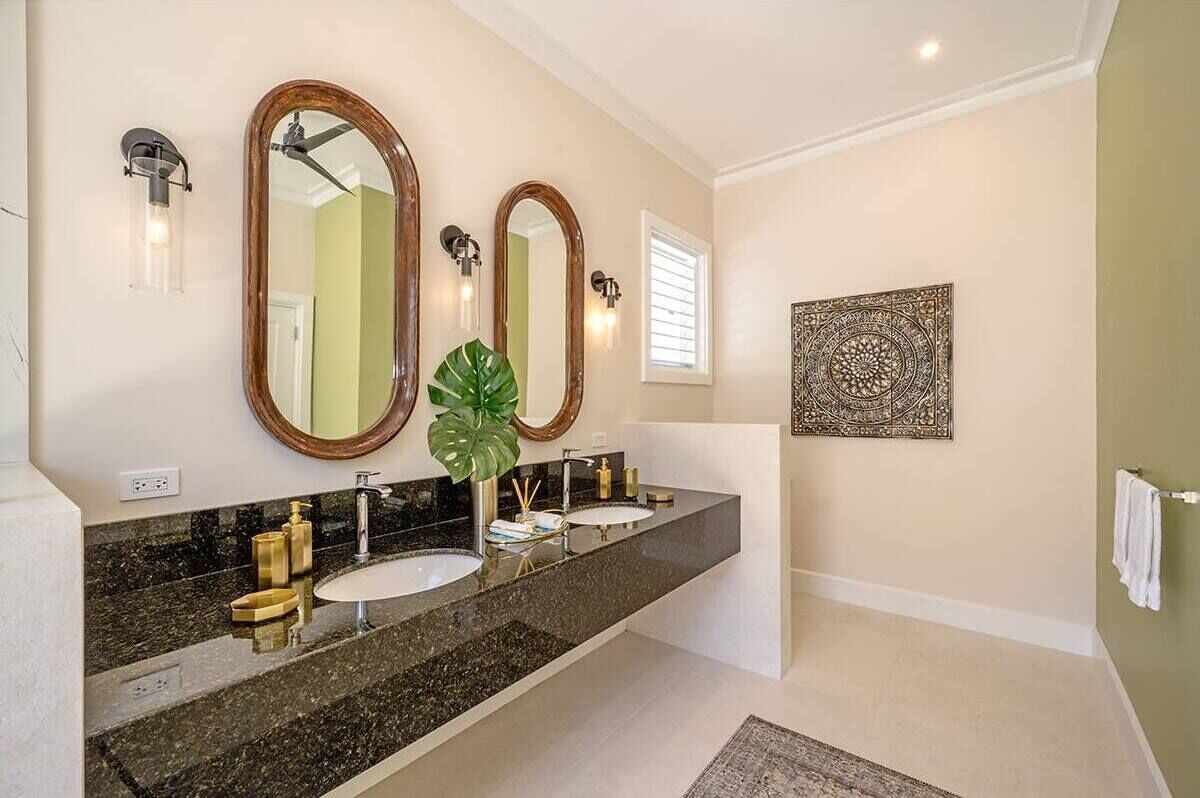 A bathroom with two sinks, a large mirror, and a decorative wall piece.