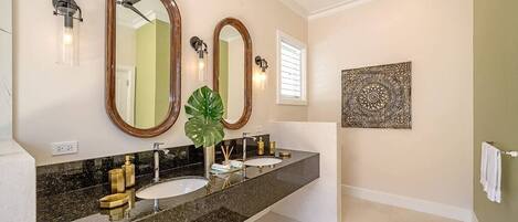 A bathroom with two sinks, a large mirror, and a decorative wall piece.