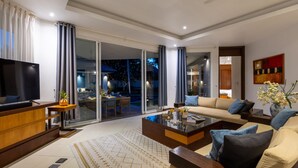 A modern living room with a TV, sofa, coffee table, and a glass door leading to a balcony.