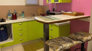 A kitchen with a sink, green cabinets, a wooden cutting board, and a bench with a patterned cushion. - Nid bleu in Schoelcher: calm, escape, sea view, nature, beaches and amenities (Schoelcher)