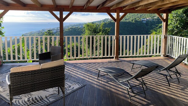 A covered outdoor deck with a view of a mountainous landscape and the sea. - Nid bleu in Schoelcher: calm, escape, sea view, nature, beaches and amenities (Schoelcher)
