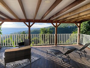 A covered outdoor deck with a view of a mountainous landscape and the sea. - Nid bleu in Schoelcher: calm, escape, sea view, nature, beaches and amenities (Schoelcher)