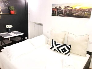 Relax in a cozy retreat with a comfortable bed, a desk for work, and a potted plant adding a touch of greenery.