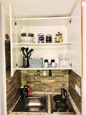 Compact kitchen with modern design, featuring a stainless steel sink, gas stove, and coffee maker.