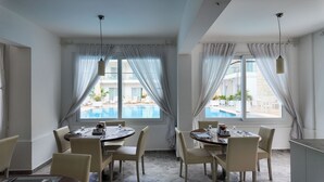 A dining area with a pool view, white walls, and a modern chandelier. - Mos Hotel Çeşme (Cesme)