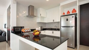 A modern kitchen with white cabinets, a black countertop, and a stainless steel refrigerator.