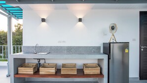 A modern kitchen with a built-in sink, a stainless steel refrigerator, and wooden storage drawers.