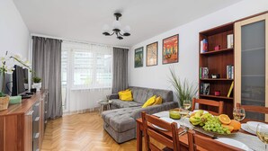 Una sala moderna con un sofá gris, una mesa de comedor de madera y una estantería.