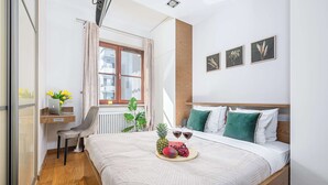 A neatly arranged bedroom with a bed, a desk, and a window. - Lumina stylish apartment with parking (Lódz)