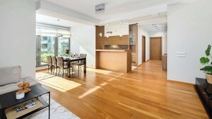 A spacious living area with a dining table, a sofa, and a kitchen area with a wooden countertop. - Lumina stylish apartment with parking (Lódz)