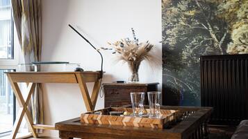 A modern living room with a wooden coffee table, a glass vase with dried flowers, and a painting on the wall.