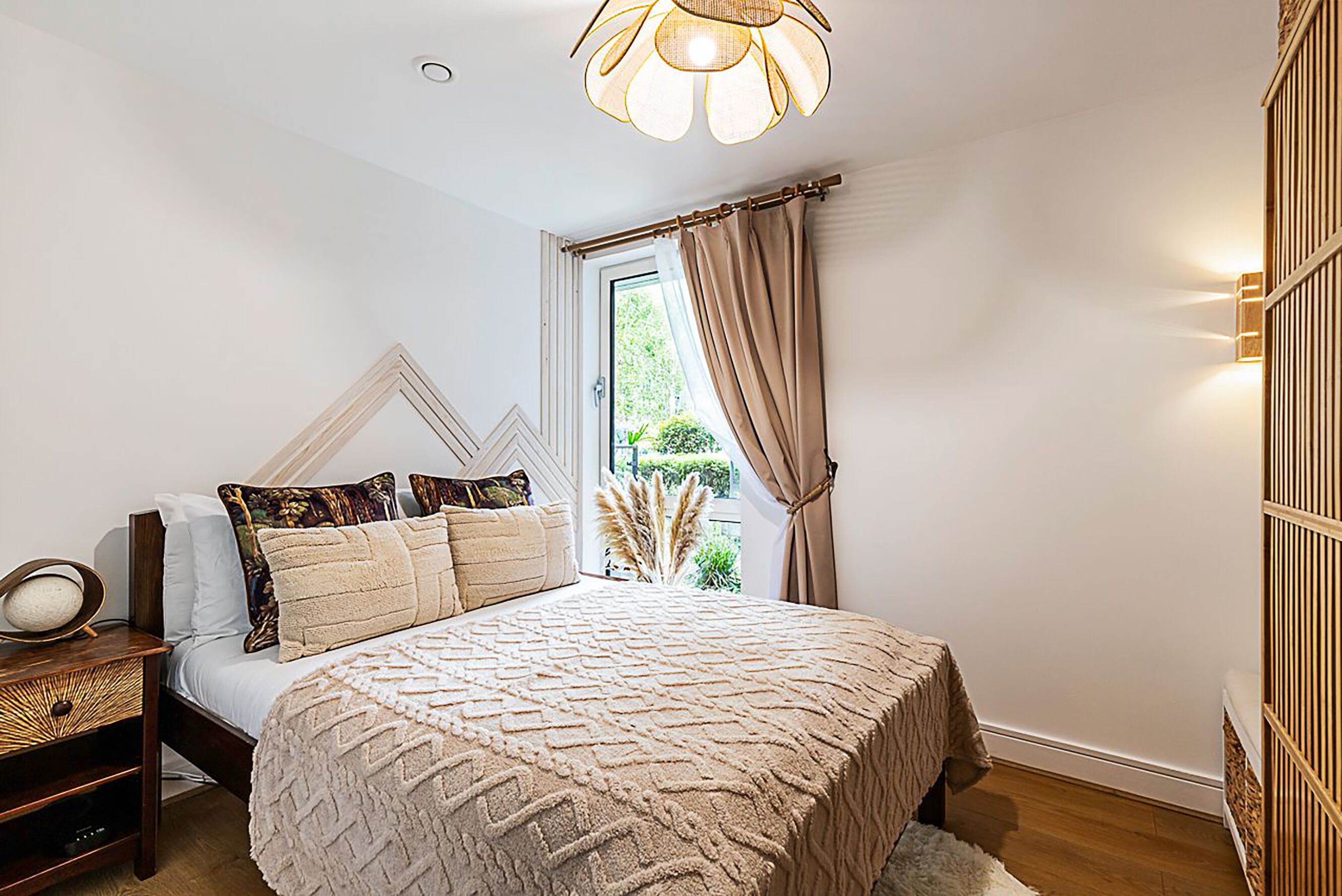 A bedroom with a bed, bedside table, lamp, and curtains.