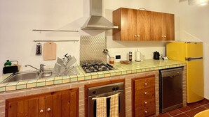 Une cuisine avec des meubles de rangement en bois, une cuisinière à gaz, un évier et un réfrigérateur jaune.