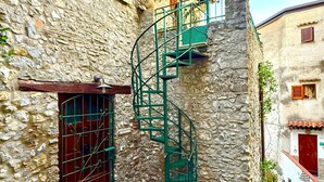Un bâtiment en pierre doté d’un escalier en colimaçon menant à un balcon en bois.