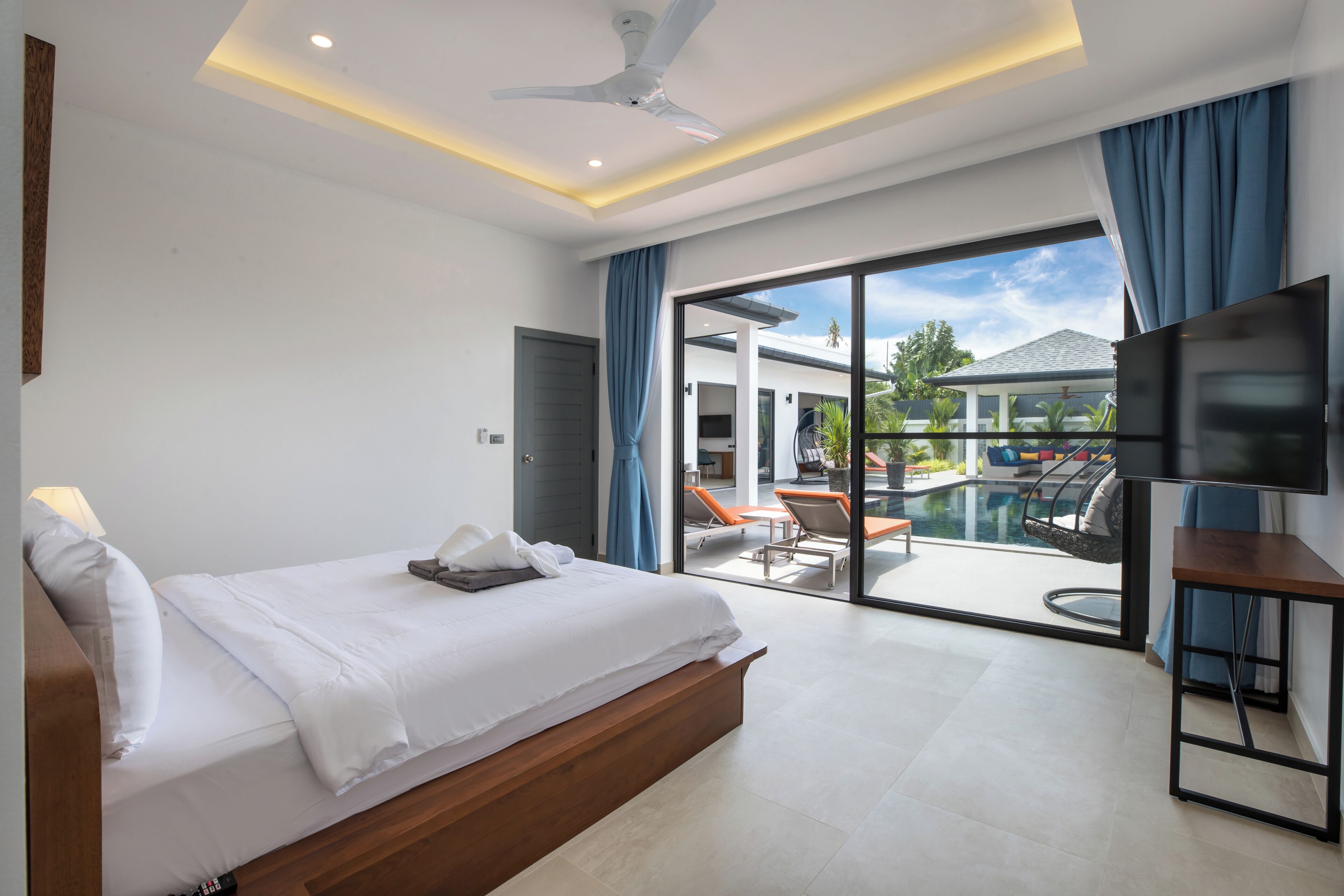 Une chambre d’hôtel moderne dotée d’un grand lit, d’une télévision à écran plat et d’un balcon avec coin salon extérieur.