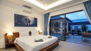 A modern hotel room with a large bed, a painting on the wall, and a balcony with outdoor seating. - Luxurious 3 bedrooms pool villa at rawai (Tambon Rawai)
