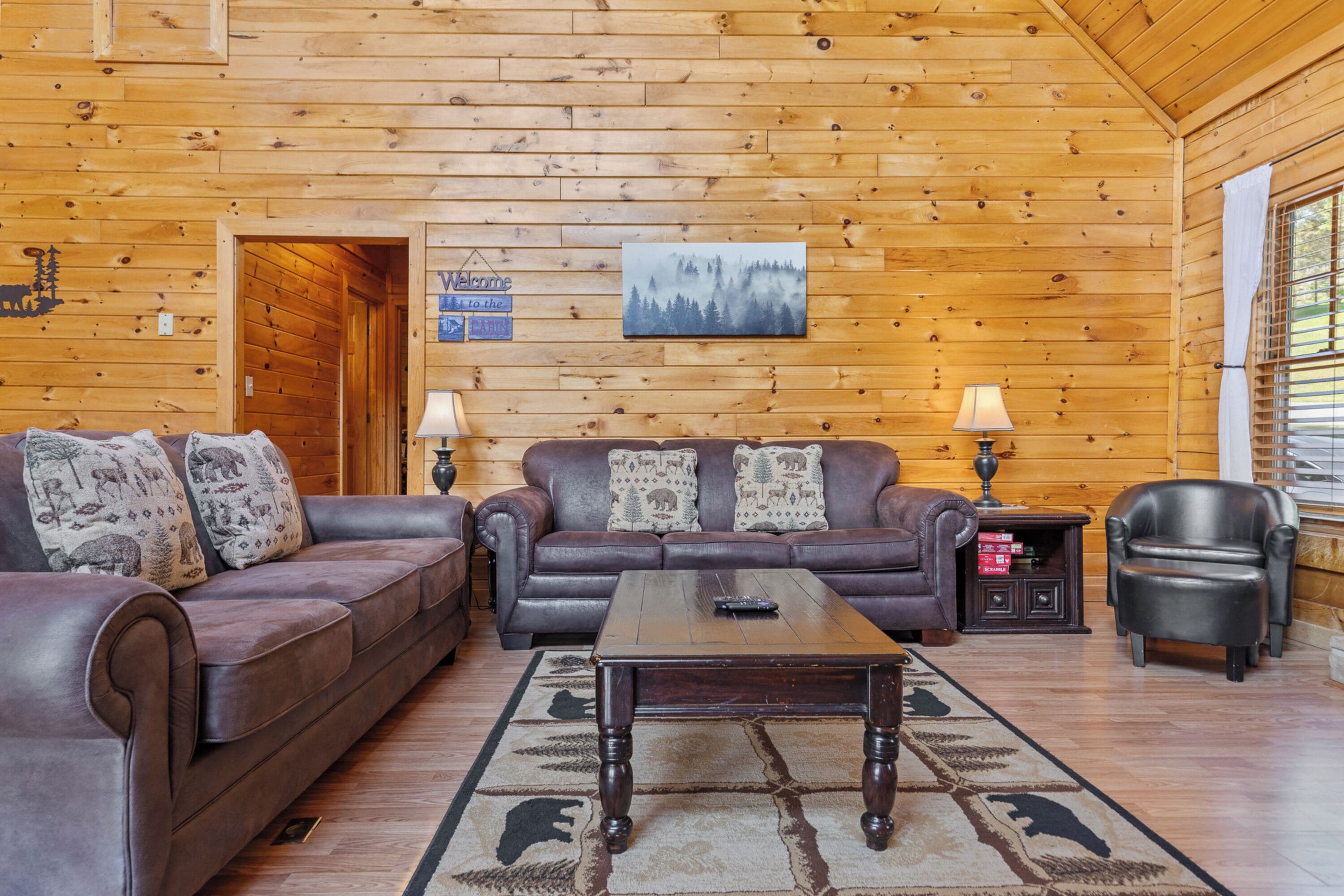 A cozy log cabin interior with two leather sofas, a wooden coffee table, and a fireplace.