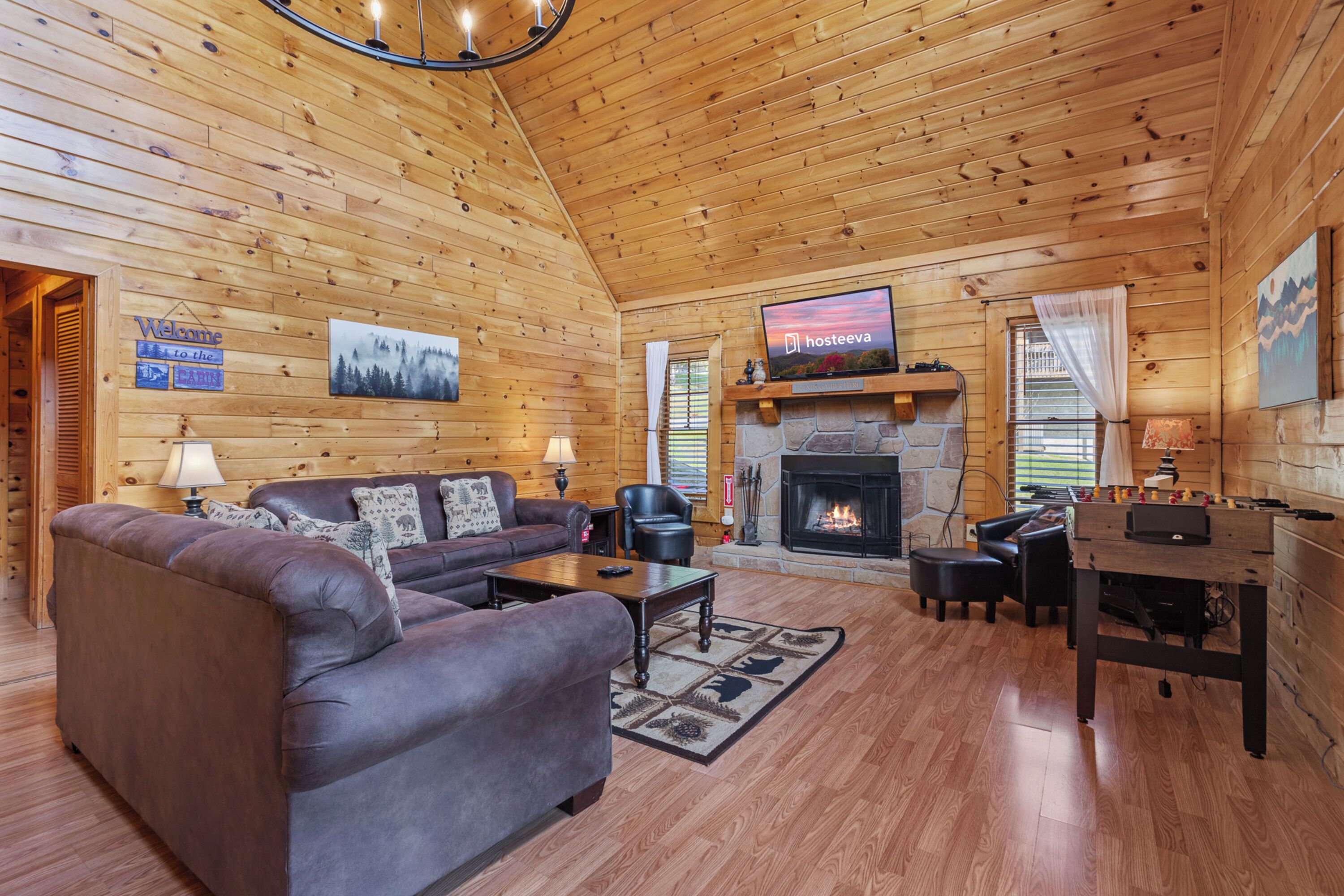 A cozy log cabin interior with a fireplace, a television, a sofa, and a coffee table.