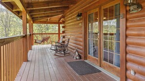 A wooden cabin with a porch, rocking chairs, and a deer figurine. - Serene Creek Cabin (Sevierville)