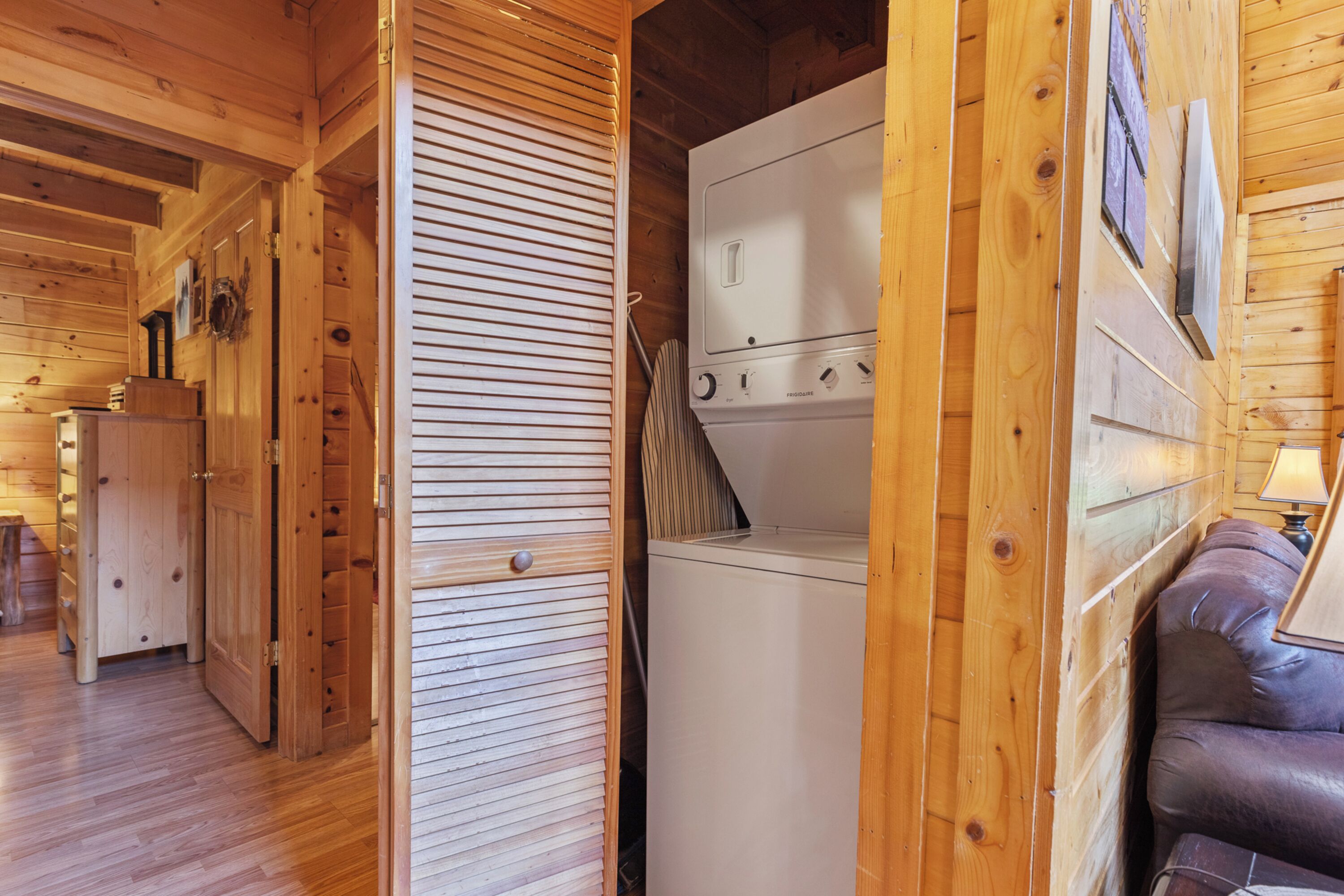 Un interior de madera con lavadora, una puerta de madera y un sofá.