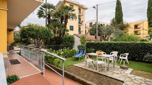 A residential courtyard with a patio area, a small play structure, and a garden with various plants. - Nice apartment for 5 guests with WIFI, A/C, TV, terrace and pets allowed (San Bartolomeo Al Mare)