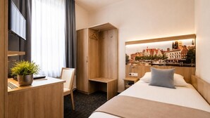 Ein Hotelzimmer mit Bett, Schreibtisch, Stuhl, Kleiderschrank und Blick auf die Stadt.
