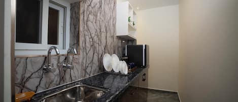 Una cocina moderna con salpicadero de mármol, pileta de acero inoxidable y estanterías integradas.