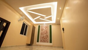 A hallway with a recessed ceiling design, a wall-mounted phone, and a door on the left. - MURALI KRISHNA APART HOTEL (Kakinada)