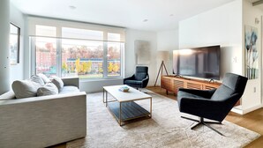 A modern living room with a sofa, armchair, coffee table, and TV. - Modern 2br-newly Built-near NYC (Hoboken)