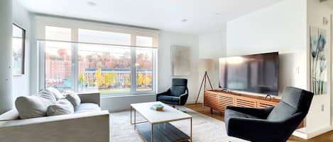 Uma sala de estar moderna com sofá, poltrona, mesa de centro e televisão.