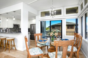 A modern kitchen with white cabinets, stainless steel appliances, and a dining area with a glass table and wooden chairs.