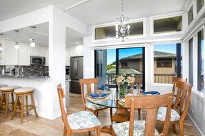 A modern kitchen with white cabinets, stainless steel appliances, and a glass dining table with chairs.