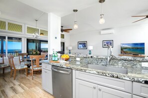 A kitchen with granite countertops, a dishwasher, and a dining area with chairs and a table.