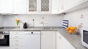 Una cocina moderna con armarios blancos, encimera de granito, lavavajillas Bosch y un lavabo.