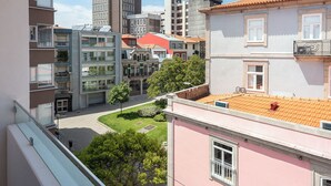 Un barrio residencial con edificios de varios pisos, un pequeño patio y un edificio rosa con balcón.