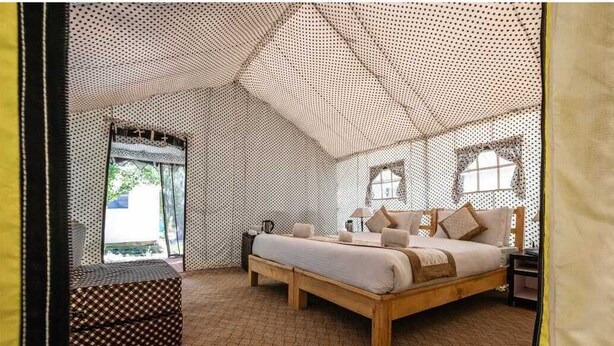 Una habitación tipo tienda de campaña con cama, banco y ventana.
