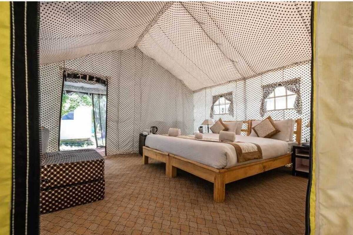 A tent-style room with a bed, a bench, and a window.