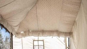 Una habitación con tienda de campaña acogedora, una mesa, sillas y un cuadro en la pared.