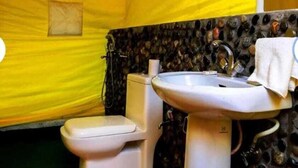 Un baño pequeño con inodoro, lavamanos y un ventanal.