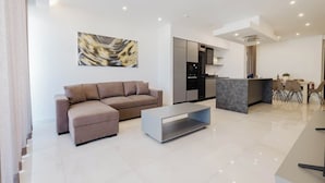Una sala de estar moderna con un sofá, una mesa de centro y una zona de cocina con una mesa de comedor y sillas.
