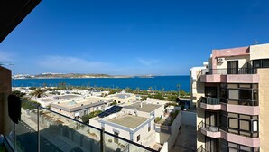 Zona residencial con vistas al mar, con edificios modernos que tienen balcones y paneles solares.