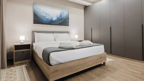 Un dormitorio moderno con una cama, mesitas de noche, un armario y un cuadro abstracto grande en la pared.
