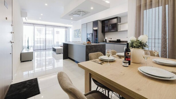 Una cocina moderna con comedor, una isla de cocina y un amplio ventanal con cortinas.