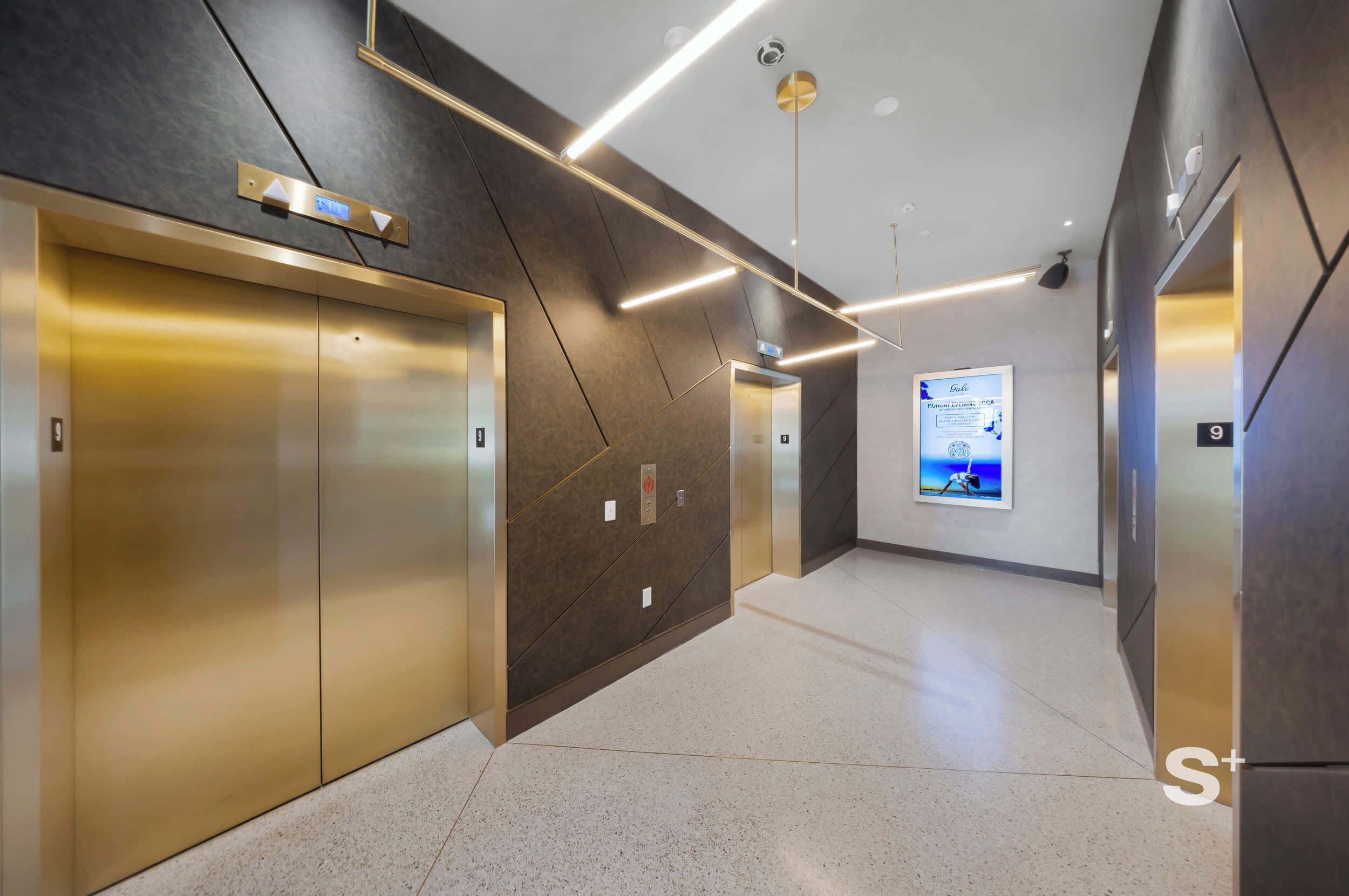 A modern elevator area with metallic elevator doors, a digital display, and a clean, tiled floor.