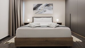 Ein modernes Hotelzimmer mit einem großen Bett, einem Oberlicht, einem Gemälde an der Wand und einem Nachttisch mit Lampe.