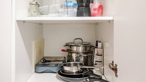 Et køkken med komfur, gryder, kaffemaskine og diverse flasker.