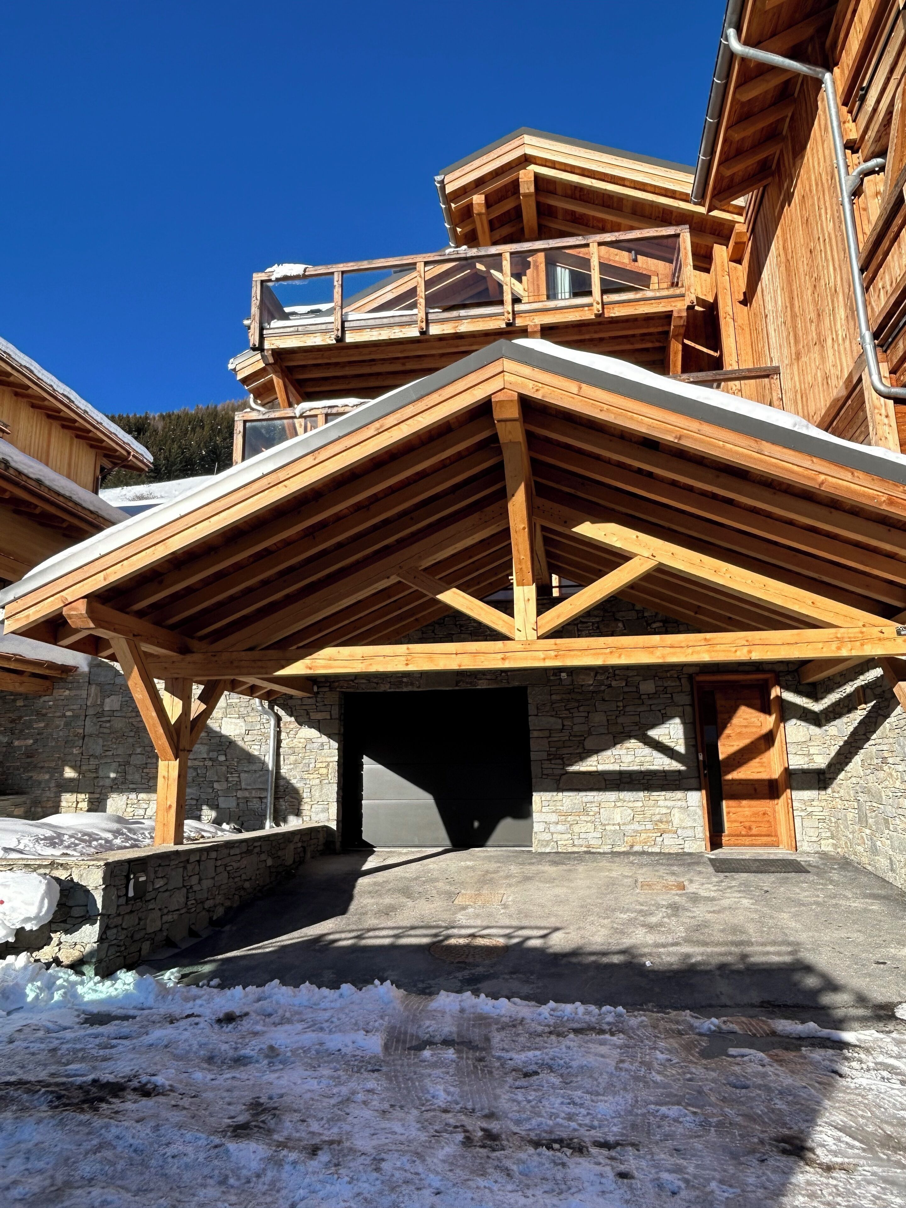 Un edificio in legno con fondamenta in pietra, un portico e terreno innevato.