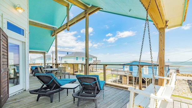 A covered outdoor deck with wicker chairs and a swing, overlooking a beach. - Ocean Breeze - 2nd Row, Best Sunrises, Surf Sounds (Freeport)