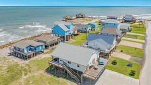A coastal residential area with houses on stilts, a beach, and a clear view of the ocean. - Ocean Breeze - 2nd Row, Best Sunrises, Surf Sounds (Freeport)
