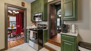 Una cocina con gabinetes verdes, una estufa y un microondas.